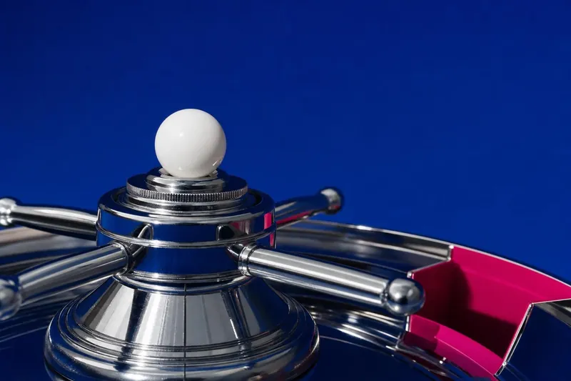 White roulette ball beside the chrome turret of a roulette wheel (AI-generated image)